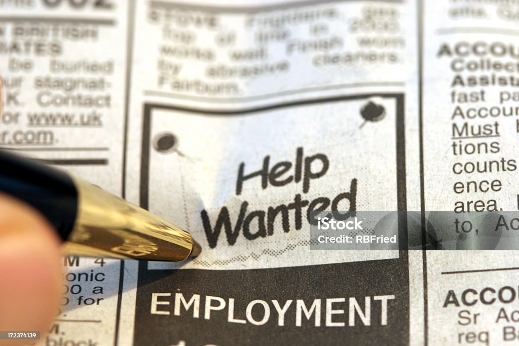 A classified ad looking for a helper a man looking at help wanted ads Job Listing Stock Photo
