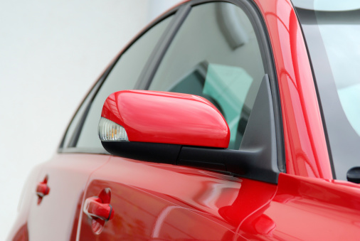Profile of red sports sedan.  Focus on mirror.