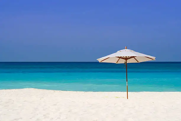 Blue sky, blue sea, white sandand a sole parasol