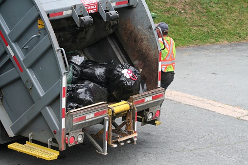Garbage truck with plastic garbage bags and worker going to next stop.