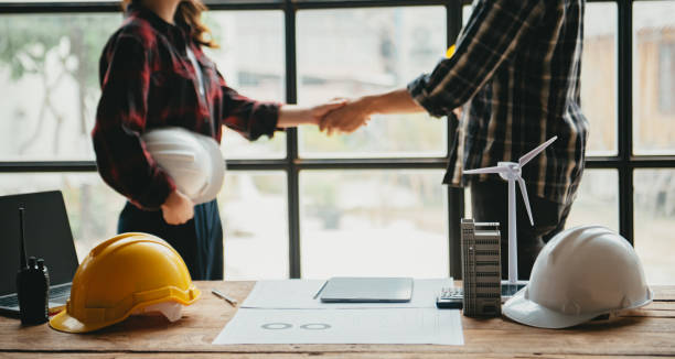 istock Construction team shake hands greeting start new project plan behind yellow helmet on desk in office center 1723779315