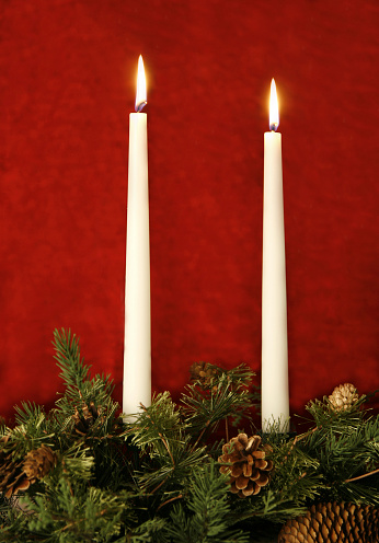 Christmas candle arrangement against red background.