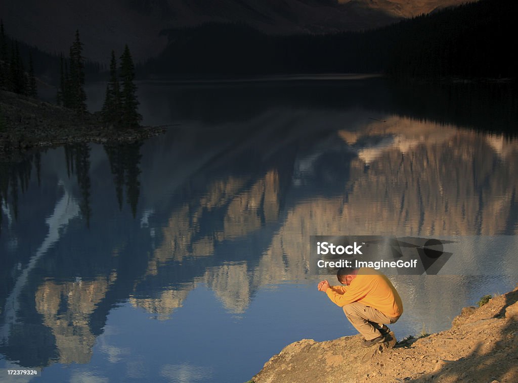 Solitude A man prays in solitude by a beautiful mountain lake. God Stock Photo