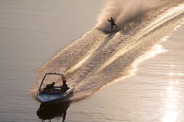 photo of man barefoot water skiing taken from bridge over lake