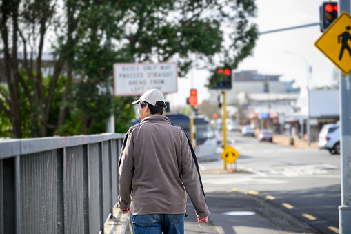 Man walking on the pedestrian sidewalk of the city street. Auckland.