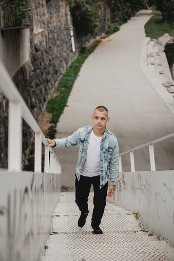 Trendy Caucasian Guy Ascending City Stairs in Urban Lifestyle. Young Man Climbing Stairs in the City. Modern Urban Exploration. Stylish Guy Climbing City Stairs. Handsome Guy Ascending Stairs.
