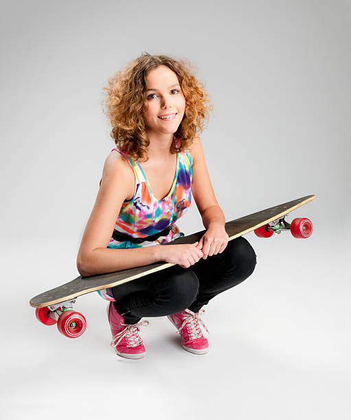 mulher jovem feliz com skate - kneeling skateboarding skateboard vertical - fotografias e filmes do acervo