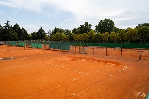 A young woman playing tennis is getting ready to take the ball in the center position. Open ground. Clay