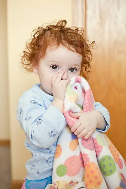 Little holding her blanket and sucking her thumb.