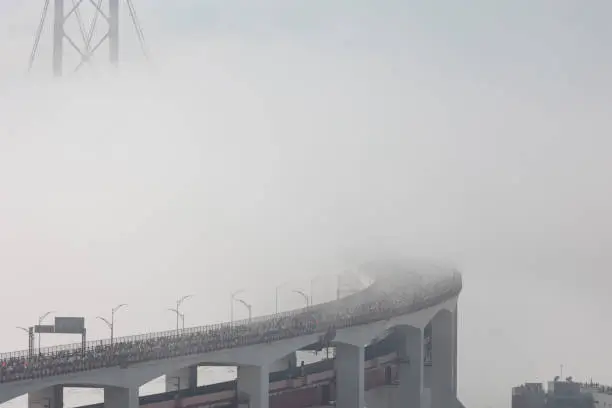 Photo of Running marathon - a crowd of people running on the bridge in a thick white fog
