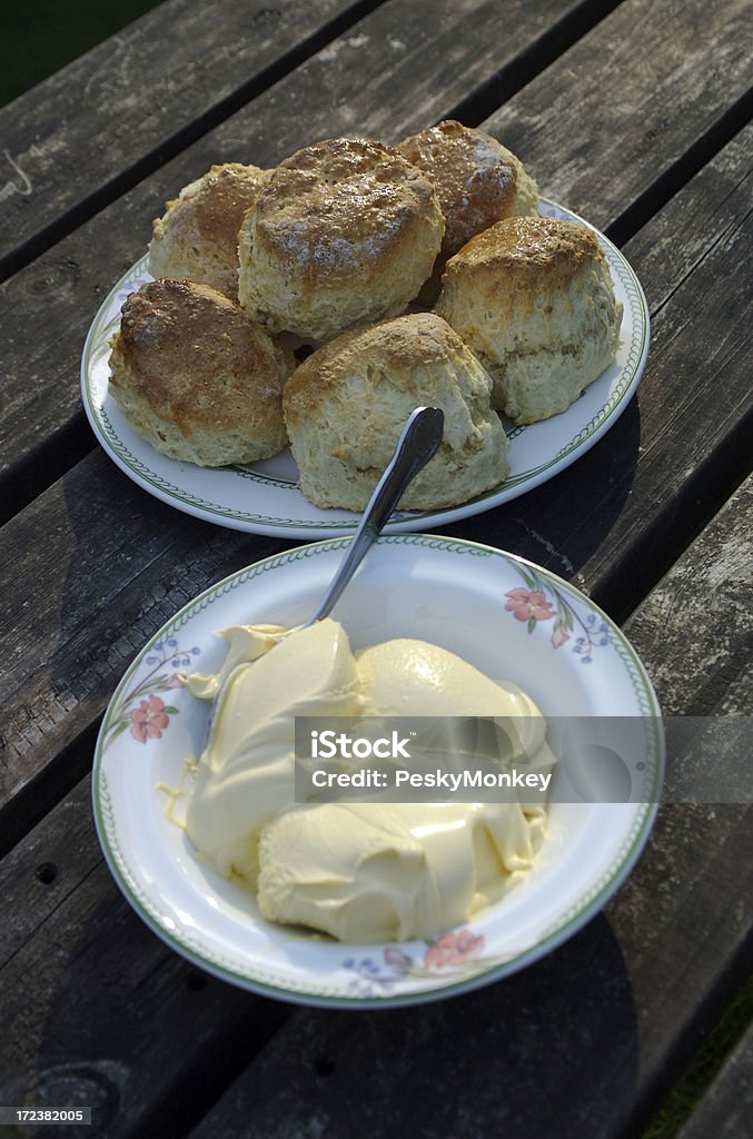 Scones and Big Dollop of Clotted Cream "Fresh baked scones and a bowl of thick Devonshire clotted cream, set out on a rustic table" Breakfast Stock Photo