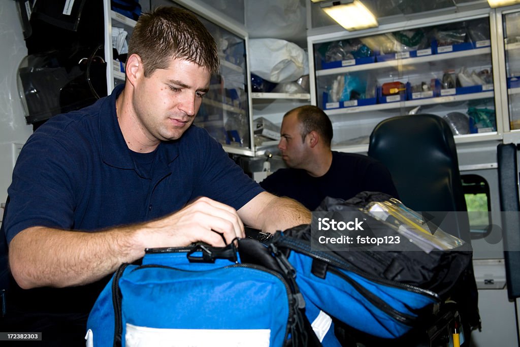 Paramedici. Uomo all'interno dell'ambulanza paramedics controllo apparecchiature mediche. - Foto stock royalty-free di Borsa