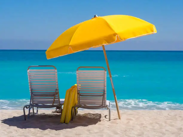 "Yellow Beach umbrella and deck chairs on the beach on a clear day on South beach, Miami"