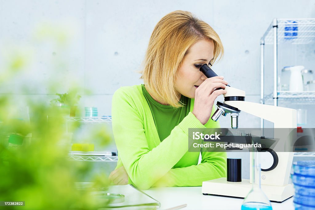 Biólogo mirando a través de un microscopio - Foto de stock de 30-34 años libre de derechos