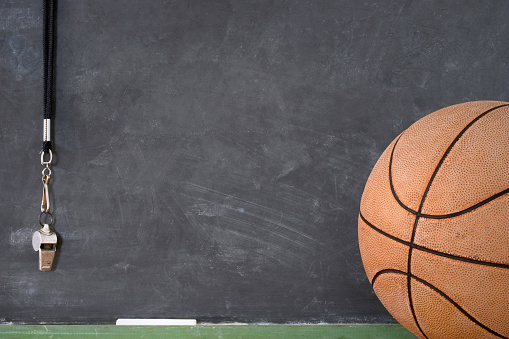 A basketball and whistle against a grunge blackboard