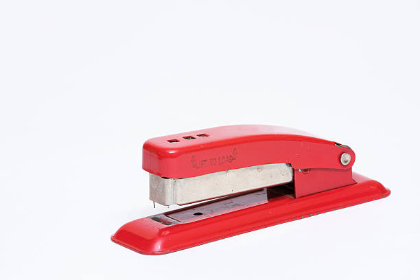 Red stapler on teal background with copy space