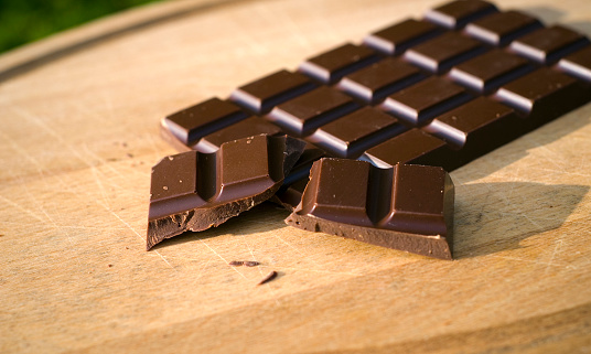Dark chocolate candy bar on a cutting board. (SEE LIGHTBOXES BELOW for many more desserts, sweet food, baking, & snack photos...)