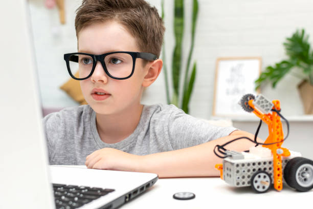 istock Clever boy in eyeglasses builds and programs a robot car using a laptop at home. The child is learning coding and programming. 1723868009
