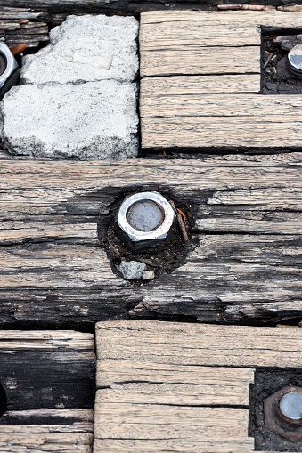 Closeup weathered wooden boards with rusty bolts and nuts, differential focus, full frame vertical compositon