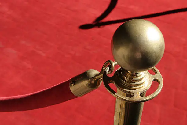 Photo of Close-up of gold stanchion holding red rope over red carpet