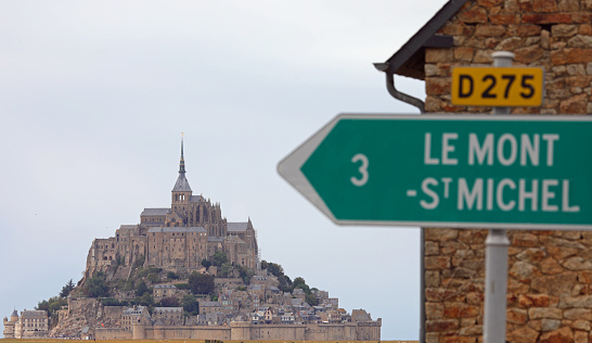 road sign with the name Mont Saint Michel and the Abbey 3 km away in the background