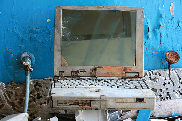 Rusted laptop with reflective screen computer among building ruins stock photo
