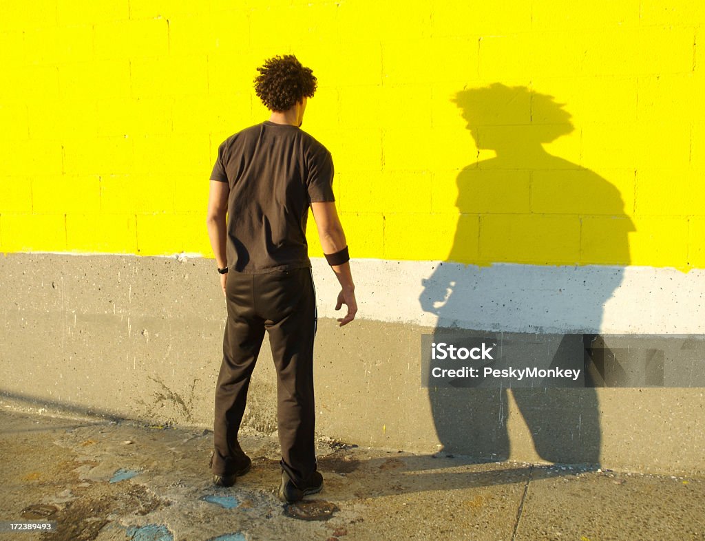 Junger Mann Afrikanischer Herkunft, steht vor seinem Schatten gelbe Wand - Lizenzfrei Männer Stock-Foto