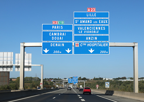 Road signs with French locations in the wide highway with three lanes with cars