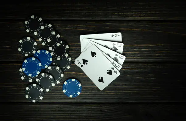 Photo of A popular poker game with a winning combination of high card. Cards with chips on a black vintage table in a poker club