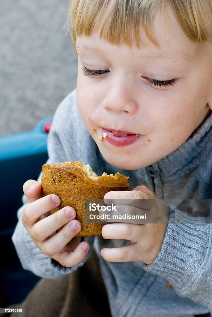 Ragazzino mangiare un muffin - Foto stock royalty-free di Mangiare
