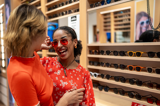 Multicultural lesbian couple trying sunglasses in a souvenir shop