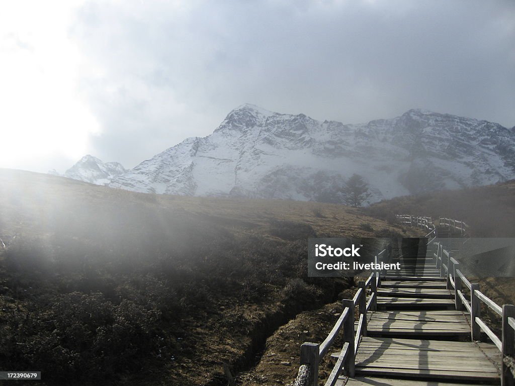 Pasaje de madera en la niebla conduce a la montaña nevada del dragón de Jade - Foto de stock de La mañana libre de derechos