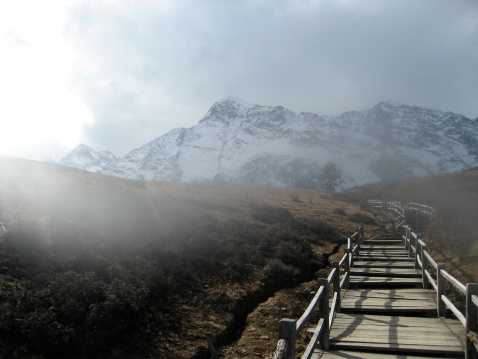 A rickety wooden walkway leads through a shroud of fog high up in the mountains in China to Jade Dragon Snow Mountain.