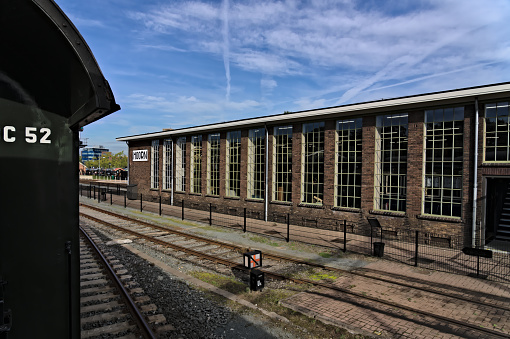 View from the railing of a historic train carriage, view of a side track and old train depot from the steam engine era at the station of Hoorn in the Netherlands