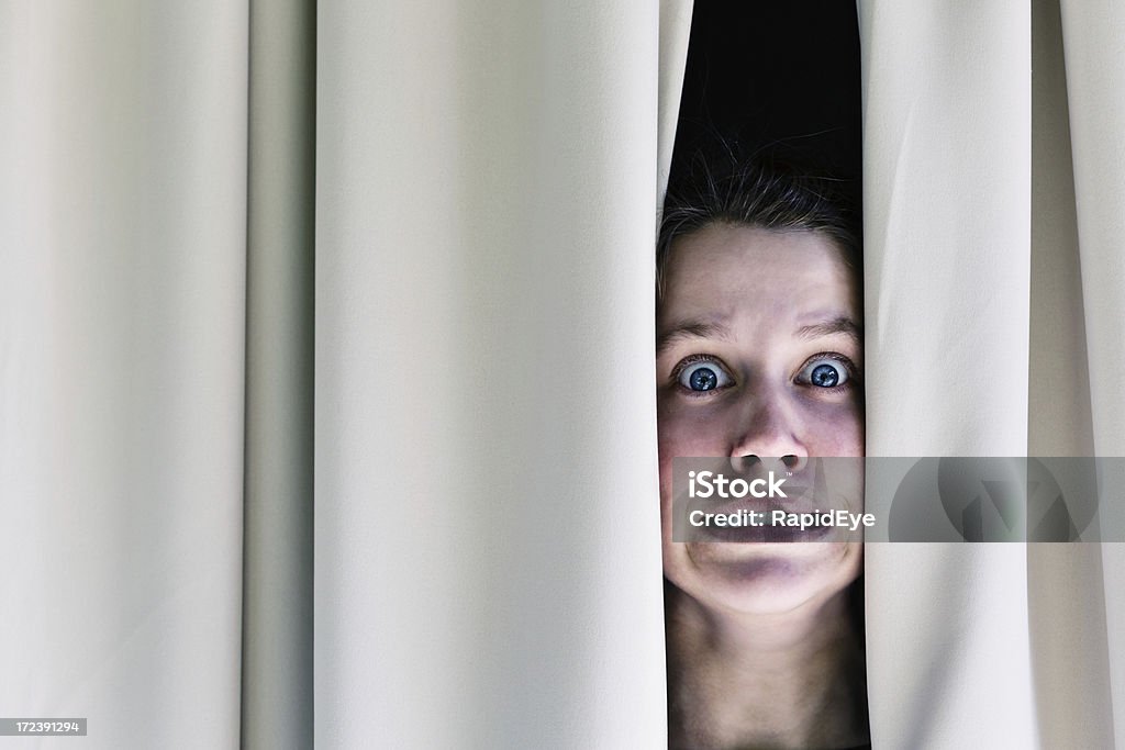 Panique Affligé jeune femme regardant à travers les rideaux de Grimace de la terreur - Photo de Adulte libre de droits