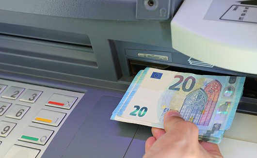 Hand of young person withdrawing twenty euros banknotes in a bank ATM in Europe