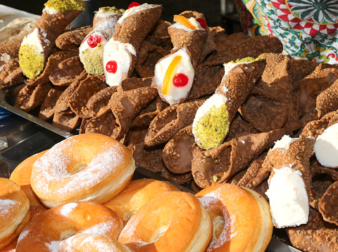 Sicilian cannoli the typical dessert of the Sicily region in southern Italy and the sugary donuts on sale in the stall
