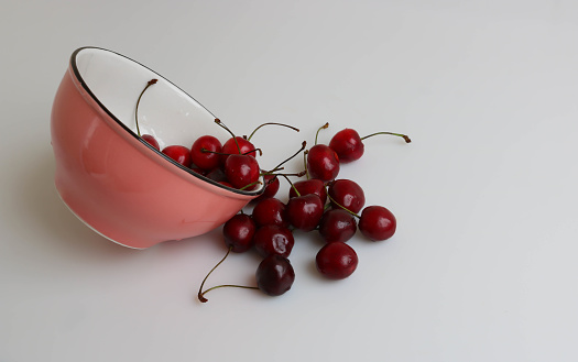 Fresh beautiful cherries from a pink bowl spilled onto the table