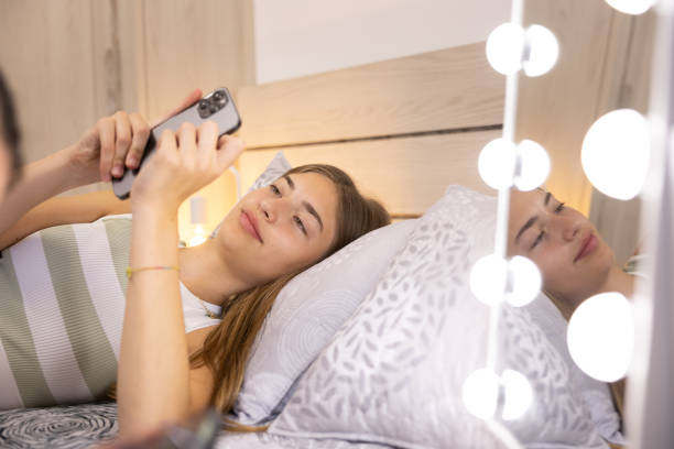 istock Young woman laying on bed looking at phone, reflected on a mirror at home interior. 1723919617