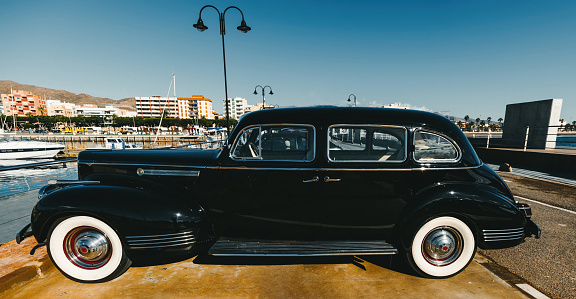 40s classic car. Black car with silver rim tires and white wheels. Side view