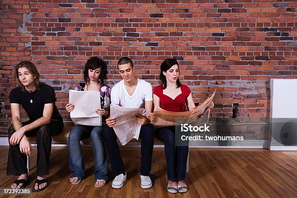 Friends Sitting On A Bench With Three Reading A Newspaper Stock Photo - Download Image Now