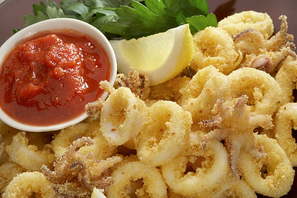 Fried calamari with marinara sauce Close up of Fried calamari with marinara sauce and lemon. calamari stock pictures, royalty-free photos & images