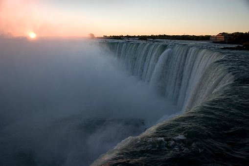 Sun breaks over horizon to expose the Niagara Horseshoe Falls .