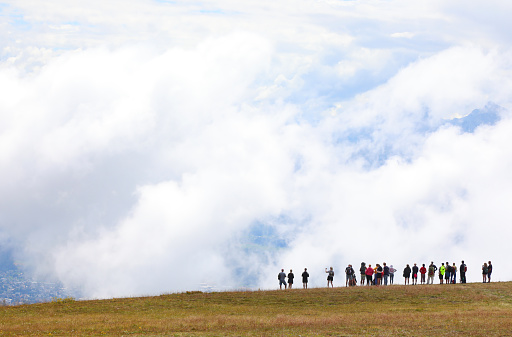 silhouettes of many people and wide panoramic view of white clouds in mountain