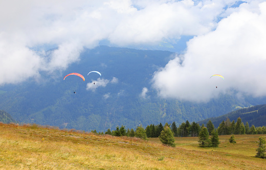 paragliders even have two people flying at the same time in the clouds in the mountains in summer