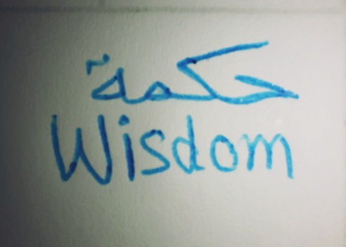 Wisdom, handwritten in Arabic, English using blue ballpoint pen ,white background