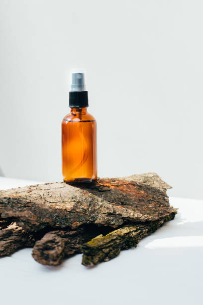 Amber spray bottle with facial treatment on a dry bark on a white background stock photo