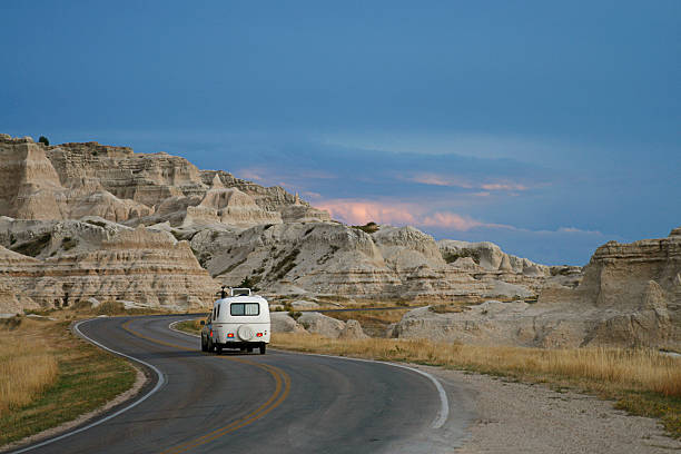 Camper at Badlands National Park A vehicle towing a retro style camper/trailer through Badlands National Park in South Dakota at sunset. badlands stock pictures, royalty-free photos & images