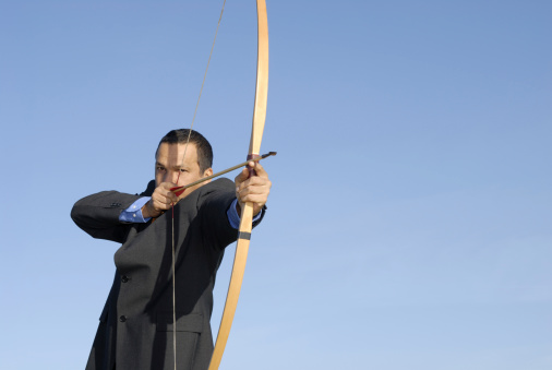 man in business suit shoots arrow