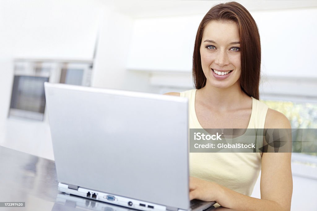 Enjoying her new laptop Cute young woman using a laptop at home Adult Stock Photo